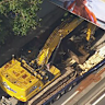 A truck carrying an excavator becomes stuck under a railway bridge over the City Link near Church Street in Cremorne on Wednesday afternoon.