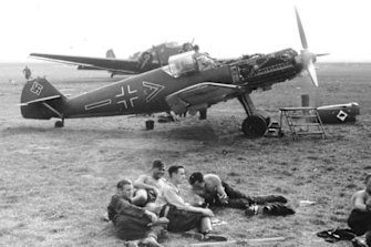 German Luftwaffe soldiers rest at an airfield in front of a Messerschmitt Bf 109.