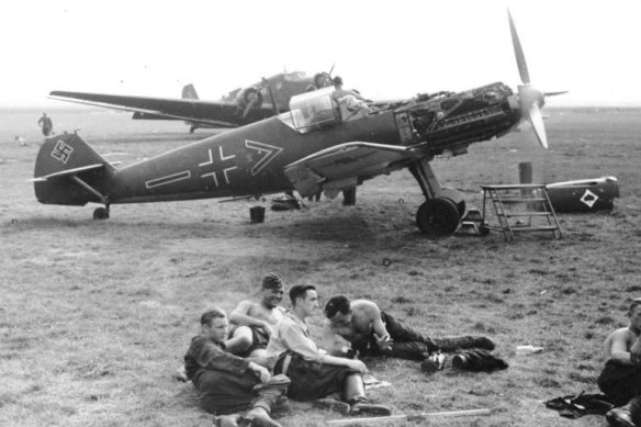 German Luftwaffe soldiers rest at an airfield in front of a Messerschmitt Bf 109.