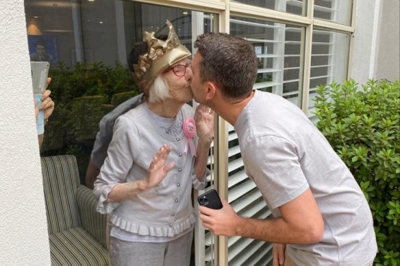 Gladys Nutbean kisses her grandson Sam Nutbean through her window on her 100th birthday on Friday.