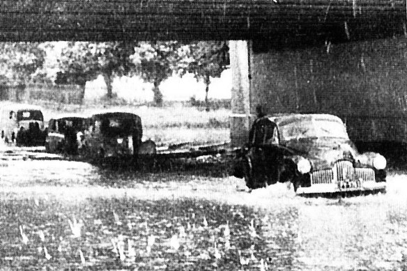 Cars plough through flood waters under the Alexandra Street bridge in South Yarra.