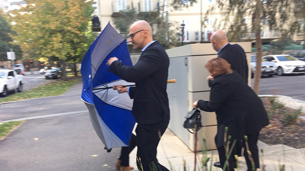 Dragi Stojanovski leaves a Coroners Court hearing in April behind an umbrella followed by his brother Vasko and mother Pisana. 
