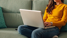 Smiling caucasian woman using laptop while sitting on a mint couch at home. Happy female shopping or chatting online in social network, typing blog, freelancer working on a project.Smiling caucasian woman using laptop while sitting on a mint couch at home. Happy female shopping or chatting online in social network, typing blog, freelancer working on a project.