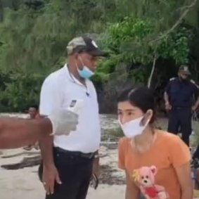 A woman has her temperature checked on the beach in Timor-Leste after arriving by boat.