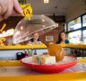 Cheeses trundle by on colour- and price-coded plates.