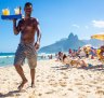 A beach vendor selling caipirinhas calls out to  customers on Ipanema Beach with Two Brothers mountain backdrop.