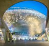 Dongdaemun Design Plaza - a Zaha Hadid-designed curving building of gleaming metal, lights up at night.