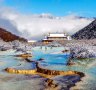 The multi-coloured pond with Huanglong Middle Temple on background in the Huanglong National Park.