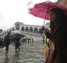 People walk near the Rialto bridge on the occasion of a high tide.
