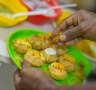 A Mumbai street-food hawker garnishes pani puri - fried pastry shells stuffed with chutney, potato, herbs and spices.