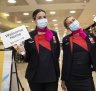 Qantas staff welcome people arriving at Sydney International Airport on Monday morning.