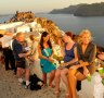 Tourists crowd walkways at Oia on Santorini as the sun sets.