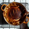 Home-made sourdough loaf in orange cast iron dish on vintage painted table Generic image of a loaf of sourdough baked in a Dutch oven casserole pot. Downloaded for Myffy Rigby cover feature on sourdough bread for Good Food May 2020.