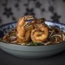 The prawn char kwai teow is tossed over high heat until smoky and soy-blackened.