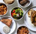 A selection of mezze including saj (bread), eggplant fatteh, fattoush, hummus, kingfish and kofta.