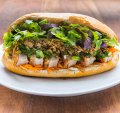 Pork belly banh mi with red curry paste, crunchy chilli oil and plenty of herbs.