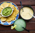 Con queso and guacamole dips with corn chips.