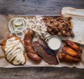 "Pitmaster selection" platter (clockwise from top right) pulled pork, buffalo hot chicken wings, brisket, house-made sausage, smoked chicken breast with Alabama-style white sauce, pickles and coleslaw.