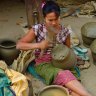 A woman beats clay waterpots into shape with  a wooden paddle at Yandabo village  near Mandalay.