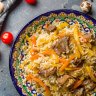 Uzbekistan's national dish and daily ritual, a hefty rice pilaf cooked with meat, onions, carrots, garlic, dried fruit, and a fair glug of oil.