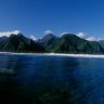 Surfer's view inside a breaking wave with lush green mountain backdrop in Tahiti.