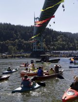 Kayakers gather as activists hang from the St Johns Bridge in Portland on Thursday. 