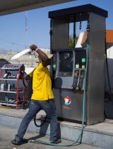 A protester hacks a gas station pump with a machete during a protest against  Michel Martelly's government.