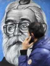 A man walks past a mural depicting Radovan Karadzic in Belgrade, Serbia. 