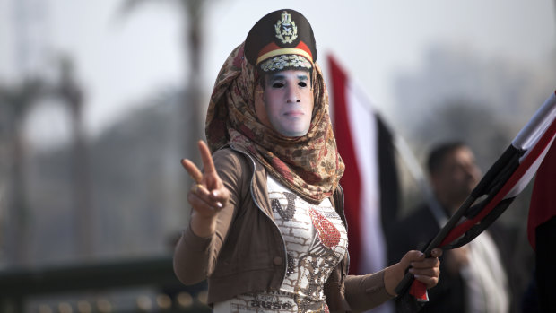 A woman wears a mask depicting Field Marshal Sisi.