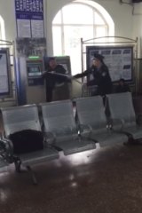 In this still image taken from cellphone video recorded on May 2 by a bystander, Xu Chunhe, left, struggles with policeman Li Lebin in a train station in Qing'an City.