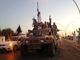 IS fighters in a commandeered Iraqi security forces armoured vehicle parading down a road in Mosul back in 2014.