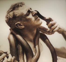The Snake Man of La Perouse offers his cheek to a red-bellied black snake. 