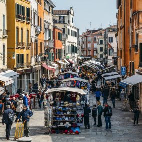 Pedestrians walk beside market stalls in Rio Tera San Leonard, in the Cannaregio district of Venice.