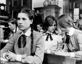 A lonely Sara Waybourne (Margaret Nelson) stares in fear as her classmates share a confidence in a classroom scene of Picnic at Hanging Rock. 