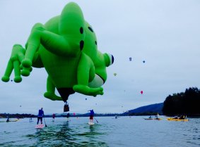 Kerbi the frog balloon gets close to stand up paddlers on Lake Burley Griffin on Wednesday morning.