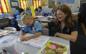 Seven-year-old Mia Chambers of Brisbane, gets on with her work under the watchful eye of teacher, Lisa Calkins, in the mobile classroom.