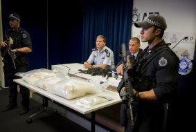 Acting Commander Paul Shakeshaft and Detective sergeant Shane Scott address the media, while armed police guard the drugs.