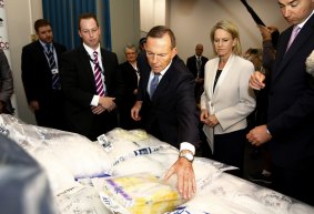 Prime Minister Tony Abbott inspects a haul of the drug ice during a press conference in Sydney on Wednesday.