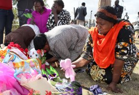 Members of the local Sudanese community grieve at the scene in Wyndham Vale where three children died and another is in a serious condition after the car, being driven by a woman, drove into the lake on Wednesday.