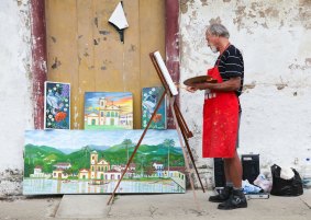 Artists paint what they see on a street in Paraty.