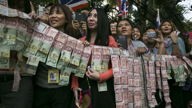Donations: Protesters hold money for Suthep Thaugsuban's campaign to bring down the government. 