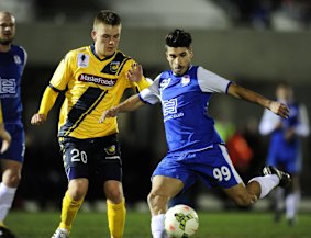 Adam Berry of Central Coast Mariners and Canberra Olympic's Jordan Tsekenis compete for the ball.