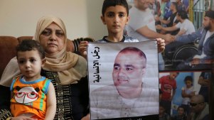 Amal el-Halabi holds her grandson Fares, 18 months old, while her grandson Amro, 7, holds a picture of his father Mohammed el-Halabi, World Vision's Gaza operations manager, who Israel accuses of diverting funds to Hamas. The alleged figures exceed the total World Vision budget for Gaza.
