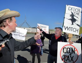 A protester defends his right to display the sign at the No Carbon Tax rally when challenged by rally organiser Chris Johnson (left) outside Parliament House in 2011. 