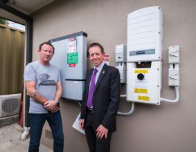Alex Humphrys and Shane Rattenbury standing in front of the battery storage system.