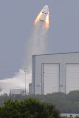 A SpaceX Dragon mock-up capsule blasts into the air.