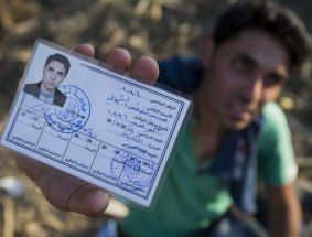 Hussein Al-Shamali, 20, from Idlib, Syria, shows his school identity card as he rests after crossing from Serbia to Roszke, Hungary. 