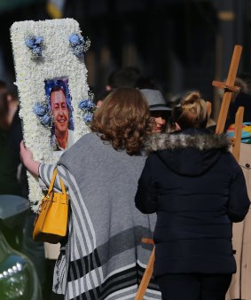 A floral tribute with a photograph of David Byrne is carried by a mourner into St Nicolas of Myra Catholic Church in Dublin during Byrne's funeral. 