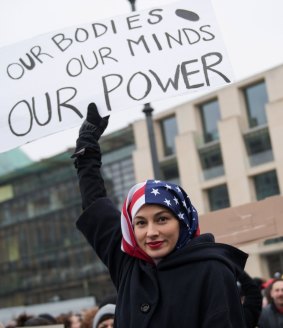 A woman wearing a USA flag as a headscarf protests in solidarity with the Women's March on Washington in Berlin, Germany. 