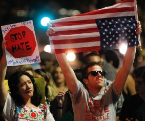 A man holds an American flag upside down as he stands with others in San Diego, to protest Donald Trump's presidential election victory. 